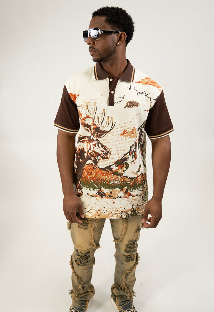 Man wearing a cream polo shirt with moose, nature-themed design on a white background
