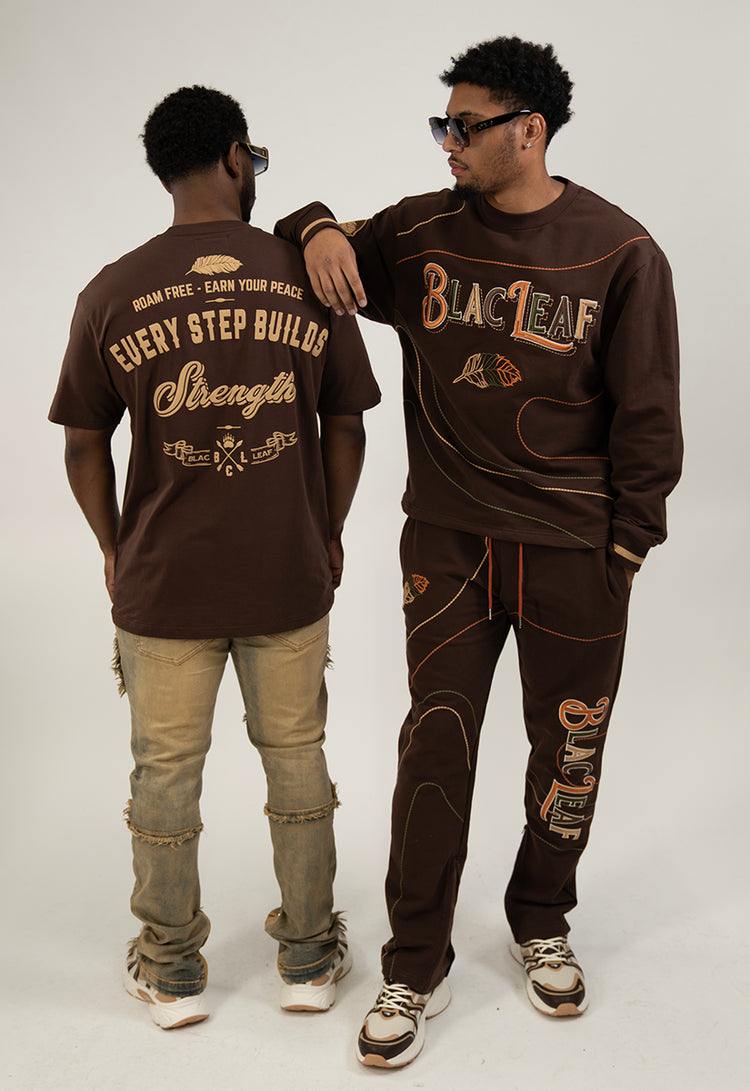 One person wearing brown outfit, brown sweatshirts and sweat pants, the other, wearing brown graphic t-shirt and distressed Jeans.