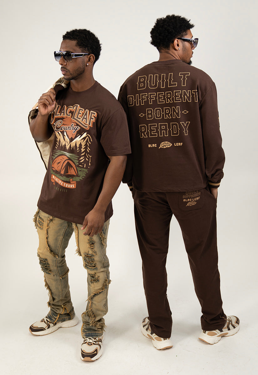 One person wearing brown outfit, brown sweatshirts and sweat pants, the other, wearing brown graphic t-shirt and distressed Jeans.