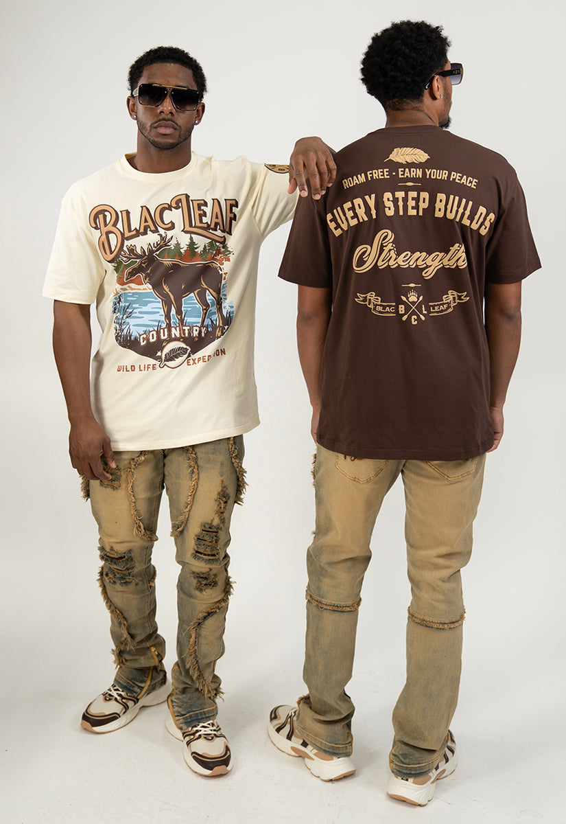 Two men wearing graphic t-shirts with visible text and distressed Jeans on a plain background