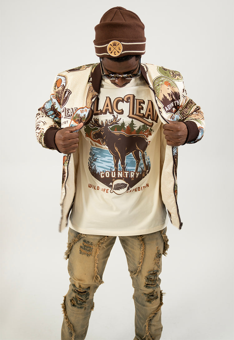 Person wearing a stylish outfit with a jacket, beanie, and graphic t-shirt on a white background