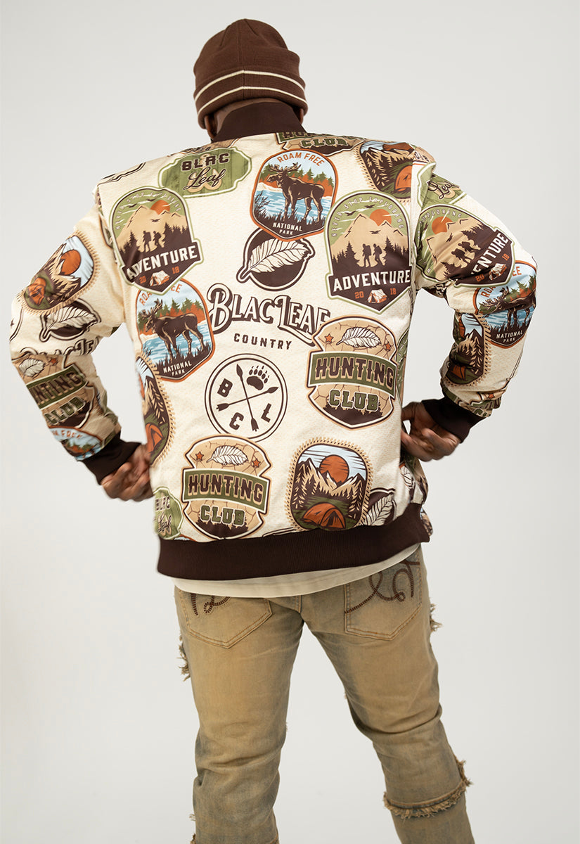 Person wearing a stylish outfit with a Reversible bomber jacket, beanie, and graphic t-shirt on a white background.
Nature graphic logos on one side of bomber jacket